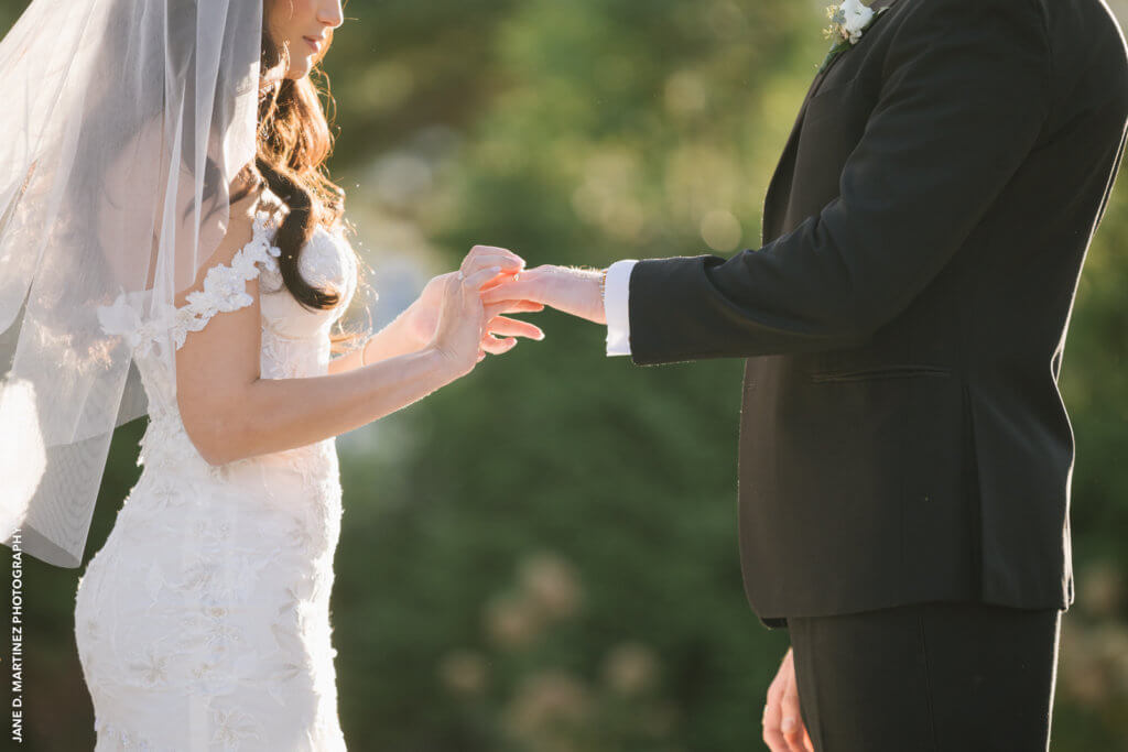 the bride placing a wedding ring on the groom's finger.