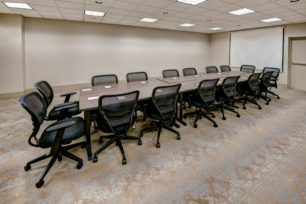 Small meeting room with a long table surrounded by rolling chairs