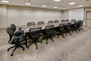 Small meeting room with a long table surrounded by rolling chairs